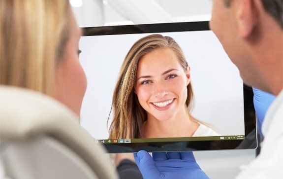 Dentist and patient looking at virtual smile design on tablet computer