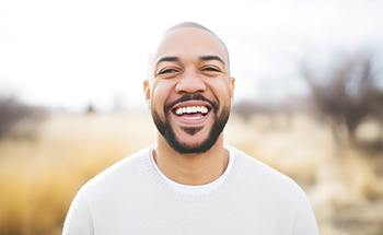 Man with white shirt smiling outside