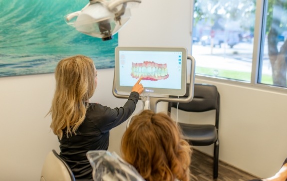 Dental team member and patient looking at digital bite impressions