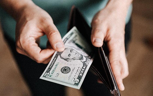 Man pulling $5 bill out of his wallet