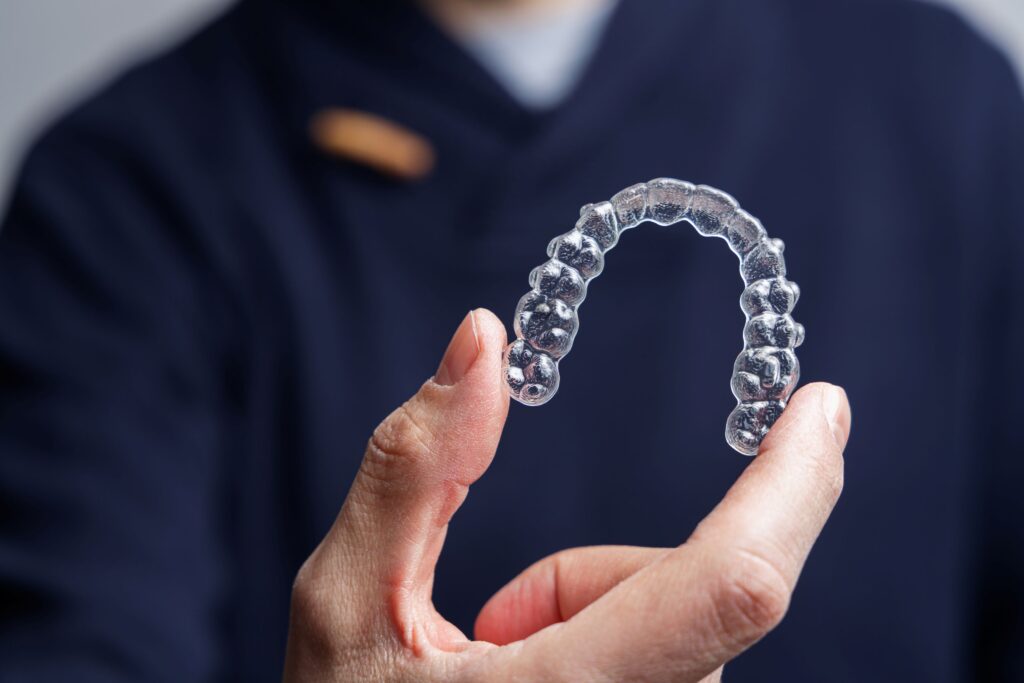 Dentist in dark blue scrubs holding Invisalign tray